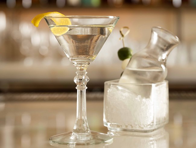 Martini cocktail served in a classic glass with a lemon twist, paired with a chilled carafe on ice.